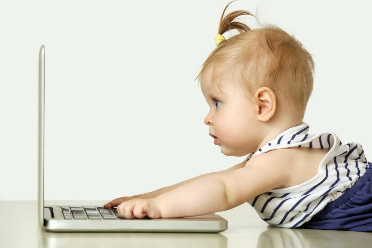 Baby lying on tummy typing on laptop
